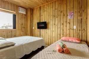 two beds in a room with wooden walls at Casa Completa com Excelente Localização in Florianópolis