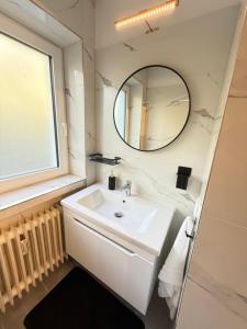 a white bathroom with a sink and a mirror at Business Apartment City 5 Betten & Parkplatz in Lüdenscheid