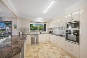 a large kitchen with white cabinets and appliances at Francis 31 in Port Macquarie