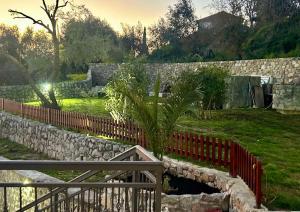 a stone retaining wall with a fence and a plant at PoolSide Residence in Kavač +27 photos
