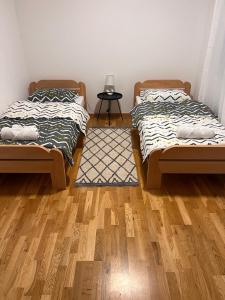 two beds in a room with a wooden floor at Apartman Park in Stara Pazova