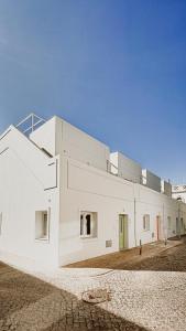 a large white building with a green door at Casa do Céu - Casas do Levante in Olhão