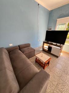 a living room with a brown couch and a flat screen tv at Casa en la Puntilla 2 in Belén