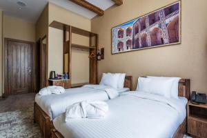 a bedroom with two beds with white sheets at Farovon Tashkent Boutique Hotel in Tashkent