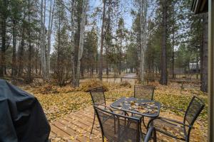 a patio with a table and chairs in the woods at 28 Quelah Condo in Sunriver