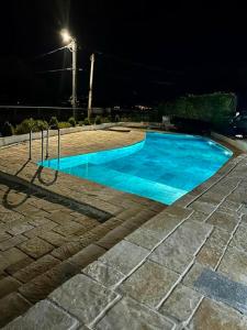 a blue swimming pool at night with a street light at PoolSide Residence in Kavač