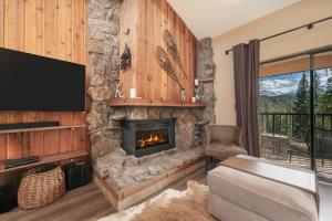 a living room with a stone fireplace and a tv at Beaver Village Unit #2031 in Winter Park
