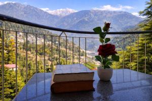 Ein Tisch mit einem Buch und einer Blume in einer Vase in der Unterkunft Hotel Cloud Hills in Dharamsala