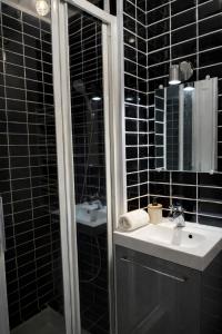 a black tiled bathroom with a sink and a shower at Le Royal Colbert - Hyper Centre - Cozy & Elegant in Tours +8 photos