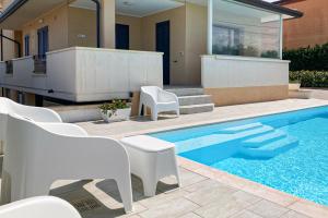a swimming pool with white chairs and a house at Villa Novelli - YourPlace Abruzzo in Fossacesia