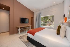 a bedroom with a bed and a desk and a window at Medellinn The Blooming Hotel in Medellín