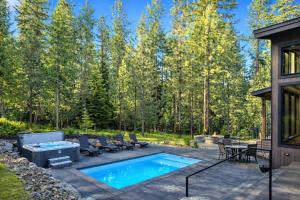 a patio with a pool and chairs and a house at Whispering Woodland in Cle Elum