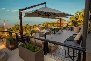 a balcony with tables and chairs and an umbrella at Villa Real Chalés in Viçosa do Ceará
