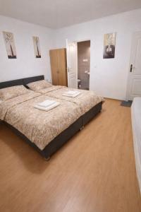 a large bed in a room with a wooden floor at Penzion Lea in Diakovce