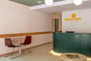 a lobby with a green counter and two chairs at Medellinn The Blooming Hotel in Medellín +189 photos