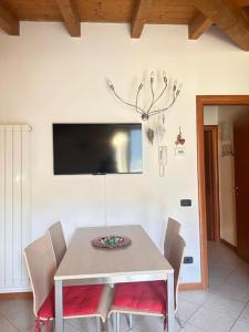 a dining room table with chairs and a television on the wall at Casa Candiotty Lake & Mountain in Endine Gaiano