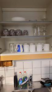a kitchen with a sink and a shelf with dishes at Station Stay Örebro in Örebro