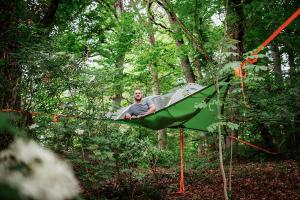a man sitting in a tent in the woods at Übernachtung im Baumzelt in Winterbach
