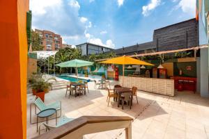 a patio with tables and chairs and a pool at Medellinn The Blooming Hotel in Medellín