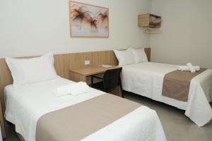 a hotel room with two beds and a desk at Hotel Jaiba Premium in Terra Fôfa