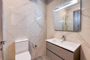 a white bathroom with a sink and a mirror at MARTINI APARTMENTs in Nikiti