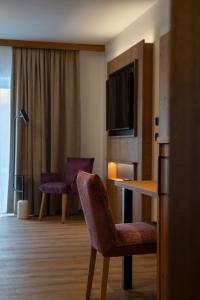 a hotel room with a chair and a table and a television at Zenger Hotel in Offenberg
