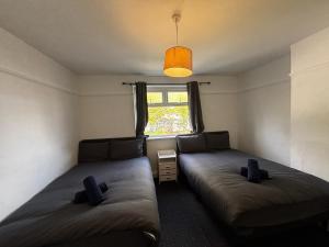 two beds in a small room with a window at Tranquil Hideaway with Hot Tub and Pool Table in Cardiff