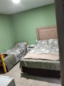 two beds in a room with green walls at BM Apart-Alojamiento in Ciudad del Este