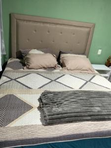 a large bed with a blanket and pillows on it at BM Apart-Alojamiento in Ciudad del Este