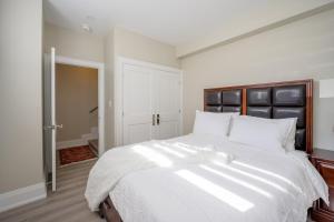 a bedroom with a large white bed with a black headboard at Beach House First Floor in Pickering