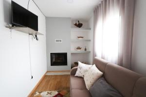 a living room with a couch and a television at Casa da Madrinha - Paredes de Coura in Paredes de Coura