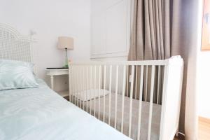 a white crib in a bedroom with a window at Casa da Madrinha - Paredes de Coura in Paredes de Coura +36 photos