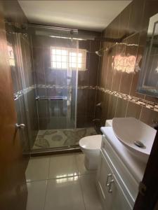 a bathroom with a shower and a toilet and a sink at Caribbean Staycation in Portmore