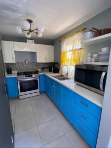 a kitchen with blue cabinets and a stove top oven at Caribbean Staycation in Portmore