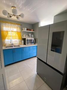 a kitchen with blue cabinets and a black refrigerator at Caribbean Staycation in Portmore