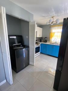 a kitchen with blue cabinets and a black refrigerator at Caribbean Staycation in Portmore +5 photos