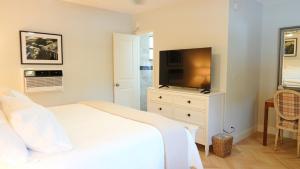 a bedroom with a white bed and a television at The Palm Rose in West Palm Beach
