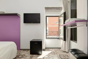 a room with a bed and a tv and a window at Gaias Rooms in Olbia