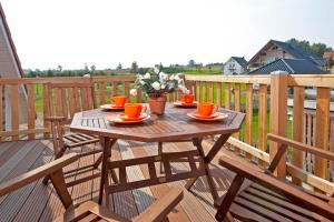 a wooden table on a deck with orange cups and flowers at Ferienhaus Mandy in Wohlenberg