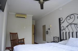 a bedroom with a bed with white sheets and a chair at Hotel Terraza Girardot in Girardot
