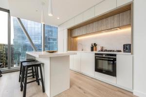 a kitchen with white cabinets and a counter with a stool at Spencer on Rock in Melbourne