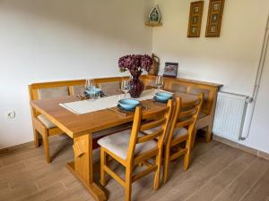 a wooden dining room table with chairs and a vase of flowers at Hiša Štanfl in Osilnica