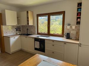 a kitchen with white cabinets and a window at Hiša Štanfl in Osilnica