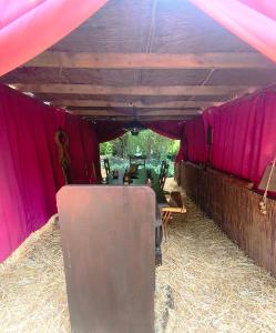 a tent with a table and pink walls and hay at Le Camp du Chevalier, hébergement insolite près du zoo de Beauval et des châteaux de la Loire in Valençay