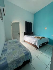 a bedroom with two beds and a blue wall at Pousada Paraiso in Canudos