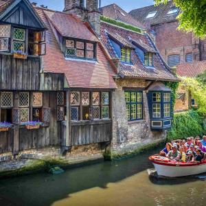 people in a boat on a canal in front of buildings at Authentiek Vakantiehuis Bos-en-Veld - Prive-tuin - Fietsvriendelijk vlakbij Brugge in Wingene