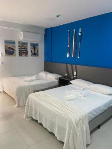 two beds in a room with a blue wall at Condomínio Aparte Hotel Laguna in Arraial do Cabo