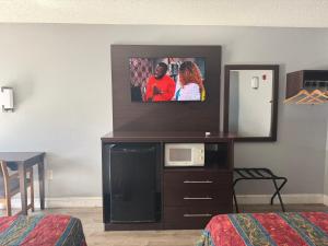 a hotel room with a tv on a dresser with a mirror at Knights Inn Ruther Glen in Ruther Glen