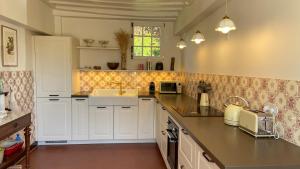 a kitchen with white cabinets and a sink at Le Clos des Grands Jardins in Giverny +3 photos