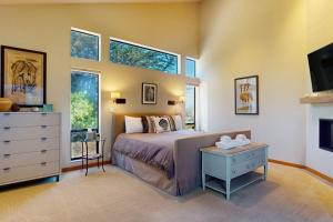 a bedroom with a bed and a dresser and windows at West Meadow in Sea Ranch